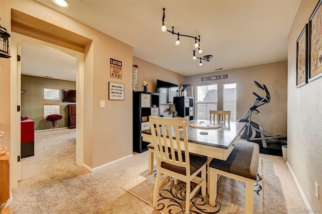 carpeted dining space featuring rail lighting