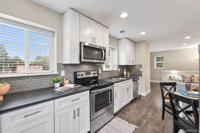 1655 N Yates St, Denver, CO 80204 - kitchen with stainless steel appliances, dark countertops, tasteful backsplash, white cabinets, and recessed lighting