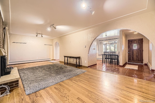 6710 W Nevada Pl, Lakewood, CO 80226 - living area with arched walkways, a baseboard heating unit, a wood stove, and wood finished floors