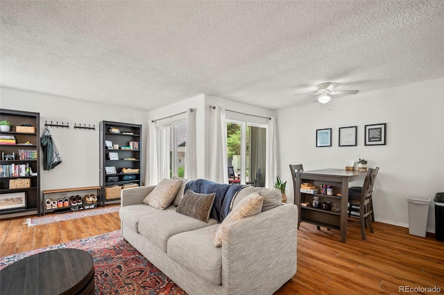 living room with ceiling fan, hardwood / wood-style floors, and a textured ceiling