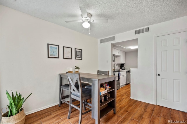 dining space with ceiling fan, sink, a textured ceiling, and light wood-type flooring