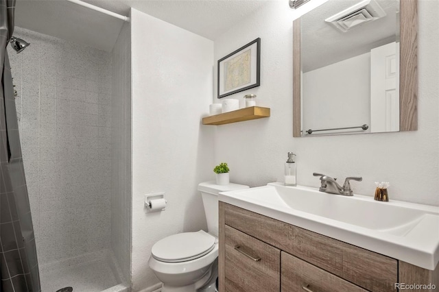 bathroom featuring vanity, tiled shower, and toilet