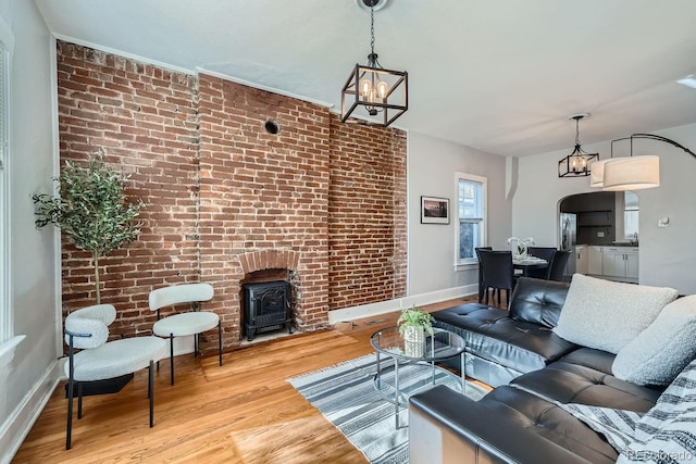 living room featuring brick wall, an inviting chandelier, and light hardwood / wood-style flooring