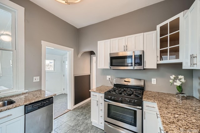 kitchen featuring white cabinetry, sink, light stone countertops, and appliances with stainless steel finishes