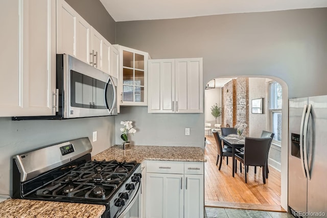 kitchen featuring appliances with stainless steel finishes, white cabinets, light stone counters, and light hardwood / wood-style floors