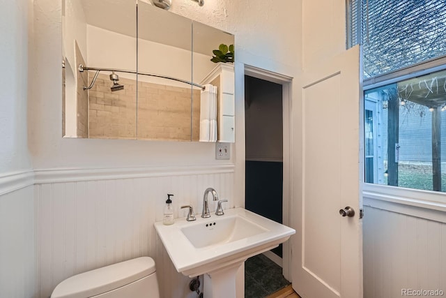 bathroom featuring toilet, sink, and a shower