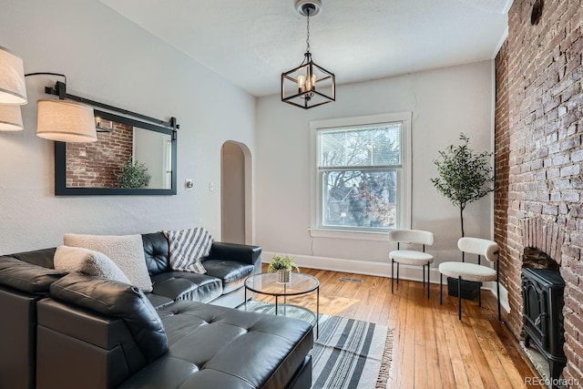 living room featuring hardwood / wood-style flooring, a chandelier, and brick wall