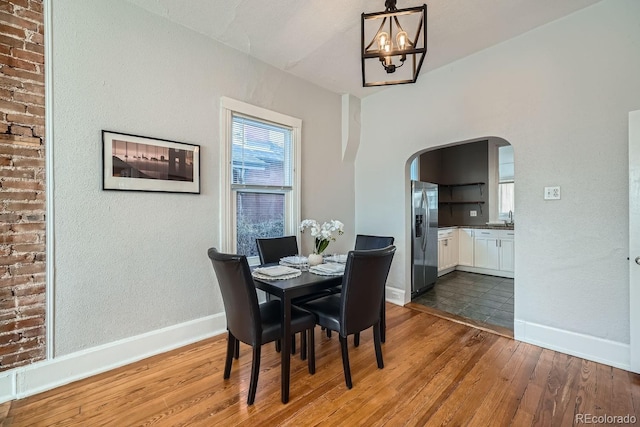 dining space with hardwood / wood-style flooring, a chandelier, and sink