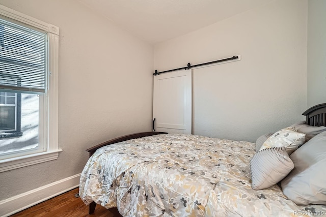 bedroom with wood-type flooring and a barn door