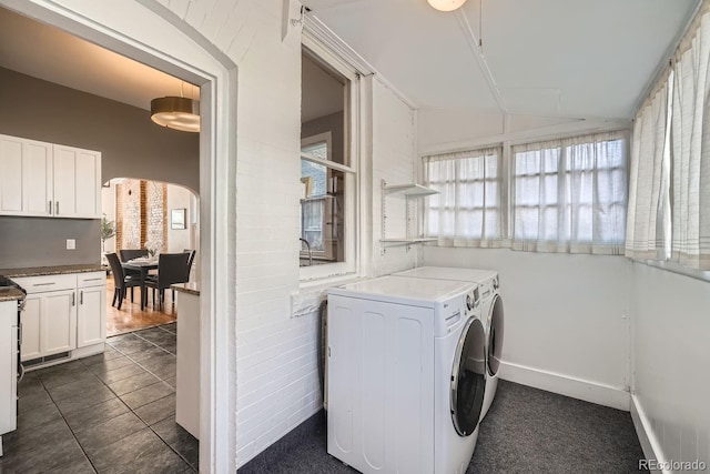 washroom featuring dark tile patterned flooring, cabinets, and washing machine and clothes dryer