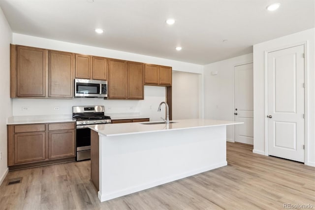 18951 E 96th Pl, Commerce City, CO 80022 - kitchen featuring stainless steel appliances, light wood-style floors, brown cabinetry, an island with sink, and recessed lighting