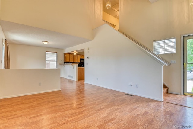 5831 Moon Ridge Dr, Colorado Springs, CO 80922 - unfurnished living room featuring light wood-style flooring, stairs, a high ceiling, and baseboards