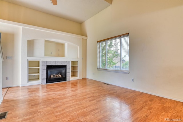 5831 Moon Ridge Dr, Colorado Springs, CO 80922 - unfurnished living room featuring wood finished floors, a tiled fireplace, built in shelves, and baseboards