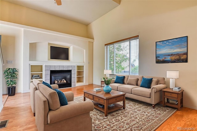 5831 Moon Ridge Dr, Colorado Springs, CO 80922 - living room with light wood-type flooring, a tiled fireplace, a ceiling fan, and baseboards