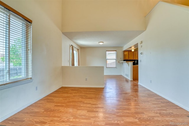 5831 Moon Ridge Dr, Colorado Springs, CO 80922 - unfurnished living room featuring light wood-style floors, baseboards, and a towering ceiling