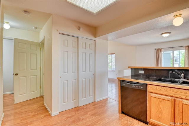 5831 Moon Ridge Dr, Colorado Springs, CO 80922 - kitchen with black dishwasher, a sink, light wood-style flooring, tile counters, and baseboards