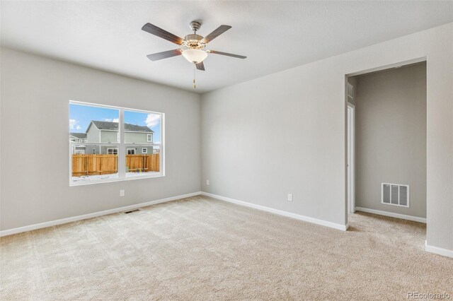 carpeted empty room featuring visible vents, ceiling fan, and baseboards