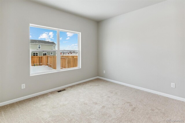 carpeted spare room with visible vents and baseboards