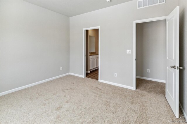 unfurnished bedroom featuring carpet floors, visible vents, baseboards, and ensuite bathroom