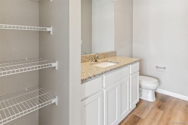 bathroom with baseboards, vanity, toilet, and wood finished floors