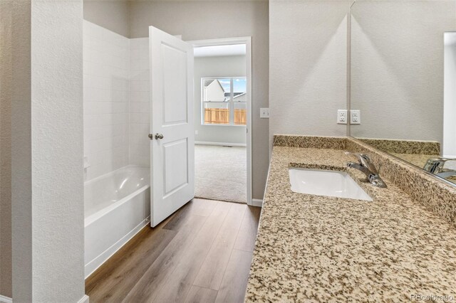 full bath with  shower combination, baseboards, wood finished floors, and vanity