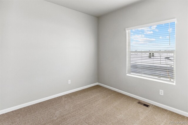 carpeted spare room with visible vents and baseboards