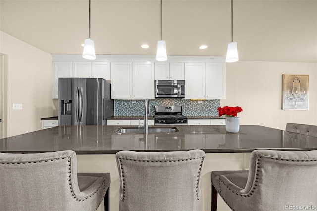8895 Vanderwood Rd, Colorado Springs, CO 80908 - kitchen with stainless steel appliances, decorative backsplash, white cabinetry, decorative light fixtures, and a breakfast bar area