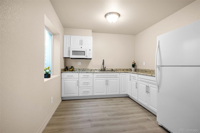 8895 Vanderwood Rd, Colorado Springs, CO 80908 - kitchen with white appliances, white cabinets, light stone countertops, and light wood-style floors
