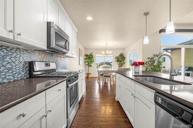 8895 Vanderwood Rd, Colorado Springs, CO 80908 - kitchen with appliances with stainless steel finishes, a chandelier, backsplash, white cabinets, and hanging light fixtures