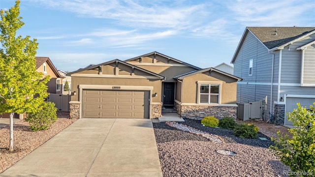 8895 Vanderwood Rd, Colorado Springs, CO 80908 - view of front of home with stone siding, stucco siding, a garage, concrete driveway, and a gate