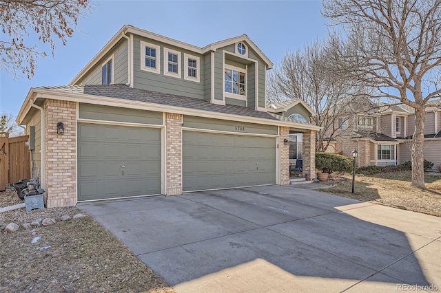 view of front facade featuring a garage, driveway, brick siding, and fence