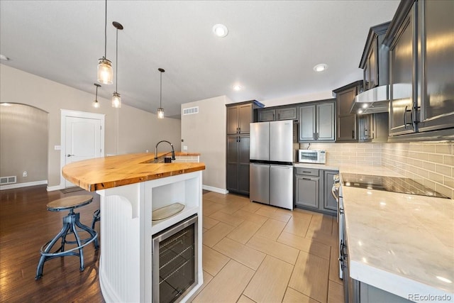 115 Quandary Ave, Berthoud, CO 80513 - kitchen featuring stainless steel appliances, wood counters, backsplash, arched walkways, and a kitchen breakfast bar
