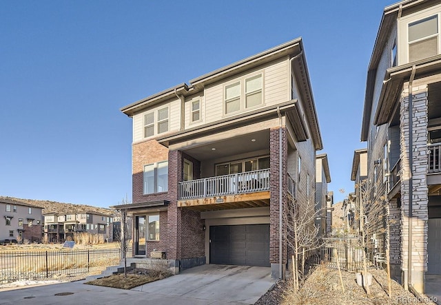 view of front facade featuring brick siding, fence, a balcony, a garage, and driveway