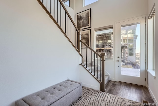 foyer with a wealth of natural light, stairway, baseboards, and wood finished floors