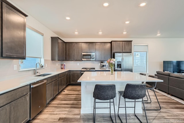 kitchen featuring a breakfast bar area, stainless steel appliances, a sink, a kitchen island, and dark brown cabinets