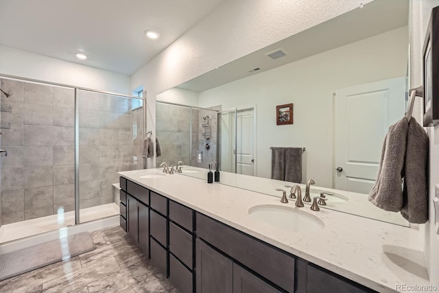 bathroom featuring double vanity, a sink, and a shower stall