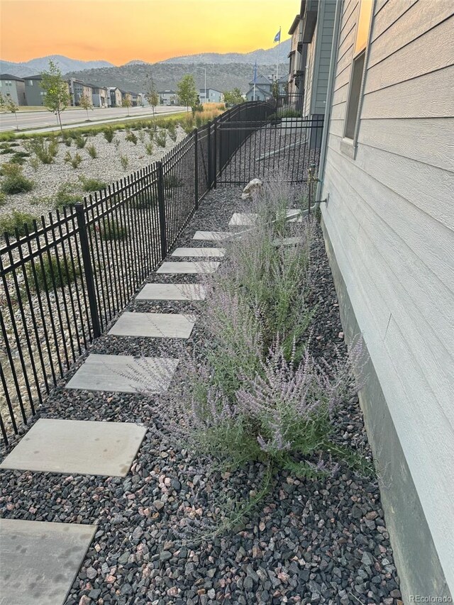 yard at dusk featuring a mountain view and fence