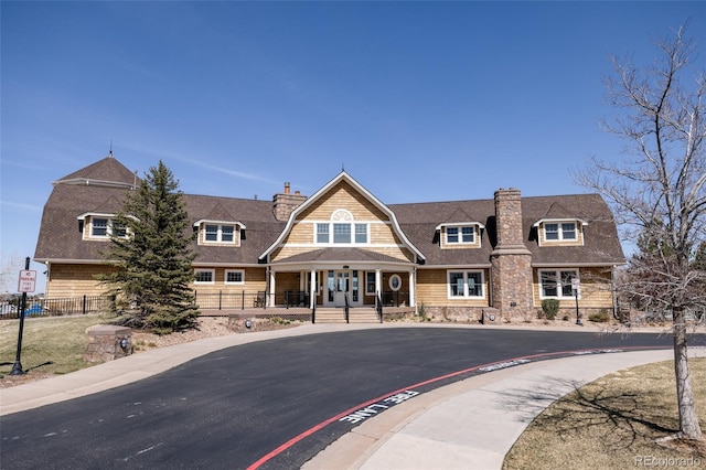 6608 S White Crow Ct, Aurora, CO 80016 - view of front of house featuring a chimney, a porch, a gambrel roof, and a shingled roof