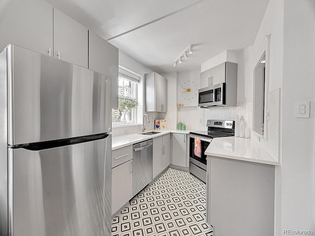 kitchen with appliances with stainless steel finishes, gray cabinetry, backsplash, and light countertops