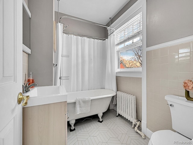 full bath featuring radiator heating unit, tile walls, tile patterned flooring, toilet, and a soaking tub