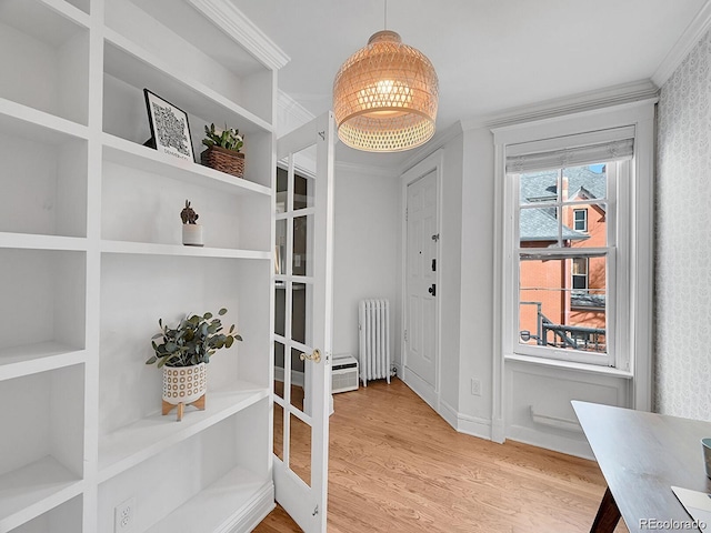 interior space with radiator heating unit, ornamental molding, and light wood-type flooring