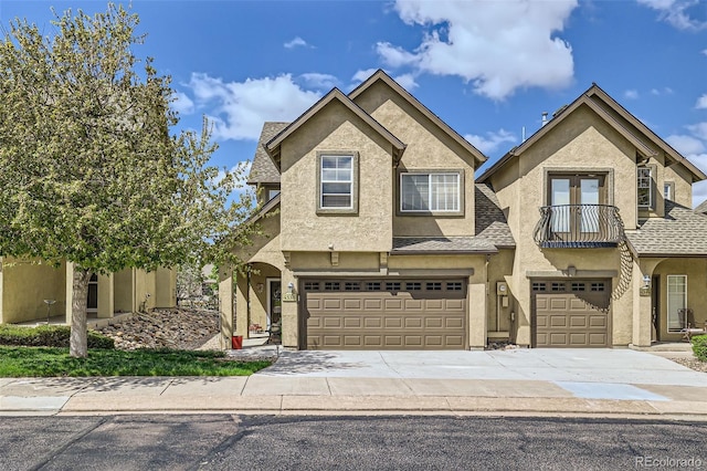 4338 Alder Springs Vw Unit G, Colorado Springs, CO 80922 - view of front of home with an attached garage, stucco siding, concrete driveway, a balcony, and roof with shingles