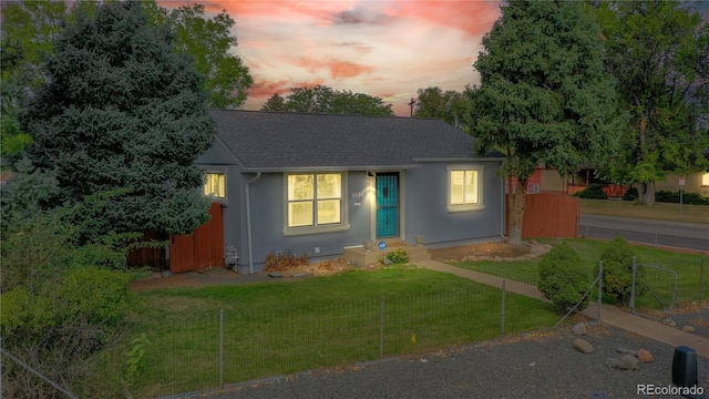 view of front of house featuring a yard, roof with shingles, and stucco siding