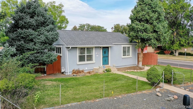 ranch-style house with a shingled roof, fence, a front lawn, and stucco siding