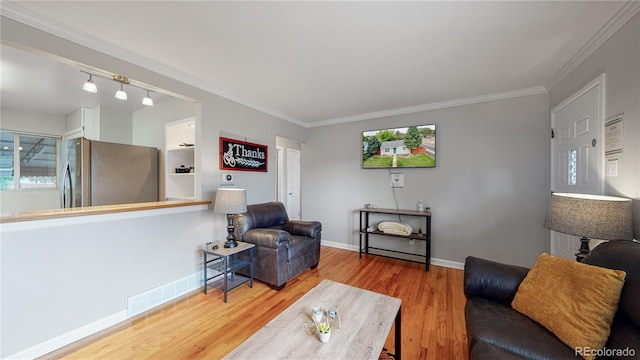 living room with visible vents, baseboards, wood finished floors, and ornamental molding