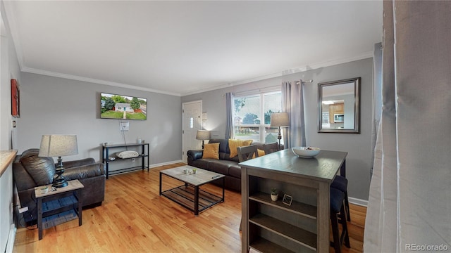 living area featuring light wood-style floors, ornamental molding, and baseboards