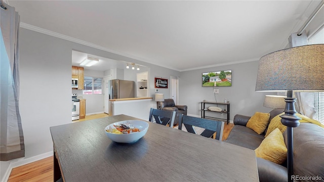 dining room featuring light wood-style flooring, baseboards, and crown molding