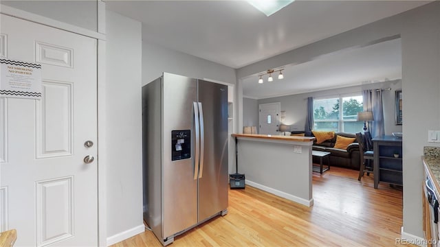 kitchen featuring light wood finished floors, stainless steel fridge, baseboards, open floor plan, and rail lighting