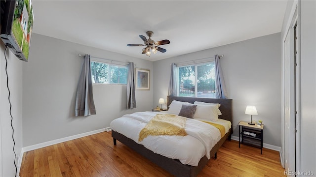 bedroom with light wood-style floors, multiple windows, baseboards, and a ceiling fan