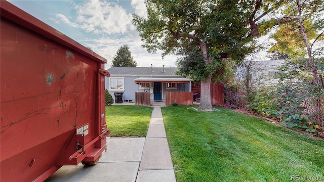 view of front of home featuring a front yard, fence, and an outbuilding